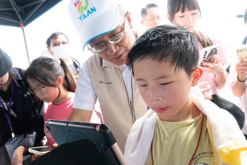 圖片說明：代理縣長與淨灘小朋友體驗AR實境解謎遊戲區，深入了解海洋保育的關鍵議題